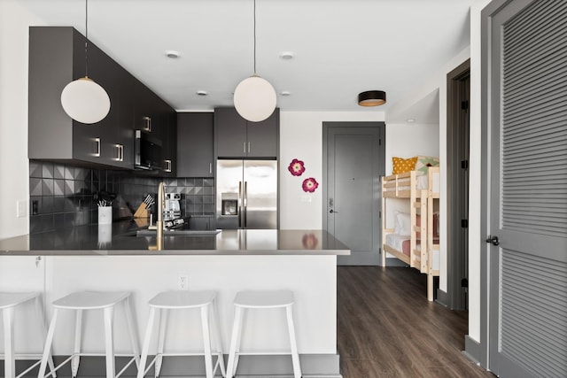 kitchen with a sink, a peninsula, stainless steel fridge with ice dispenser, decorative backsplash, and dark wood-style flooring