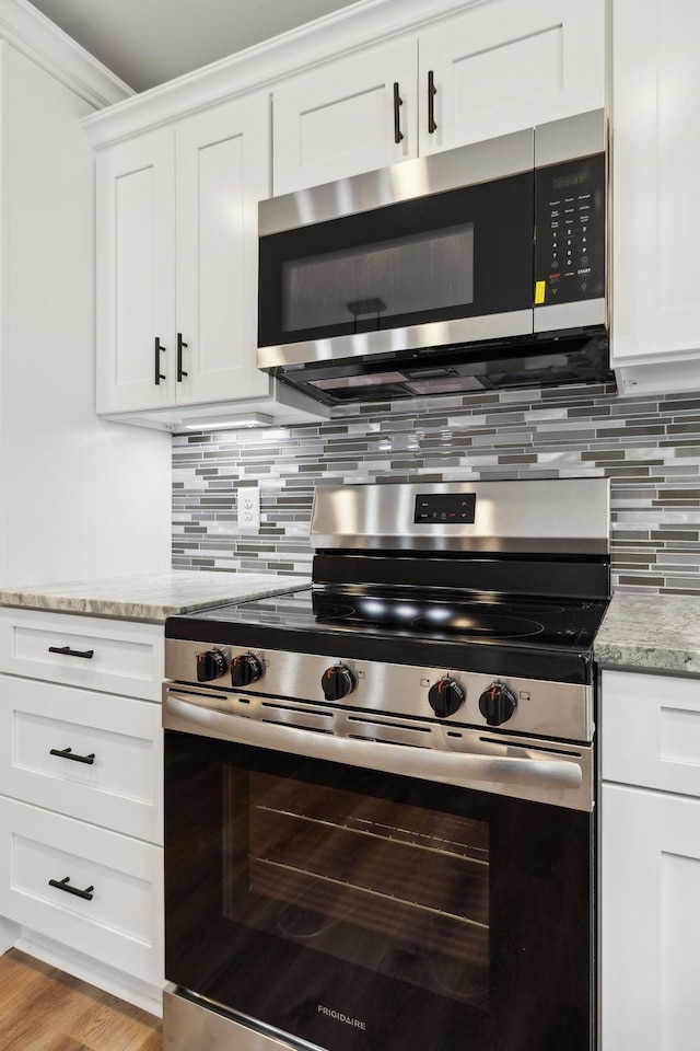1507 New Harmony Rd, Hartsville, TN 37074 - kitchen featuring stainless steel appliances, light stone countertops, decorative backsplash, white cabinets, and crown molding