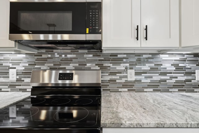 1507 New Harmony Rd, Hartsville, TN 37074 - kitchen view of stainless steel range with electric stovetop, light stone countertops, white cabinets, and decorative backsplash