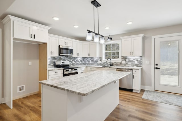 1507 New Harmony Rd, Hartsville, TN 37074 - kitchen with appliances with stainless steel finishes, a sink, white cabinets, decorative backsplash, and a kitchen island