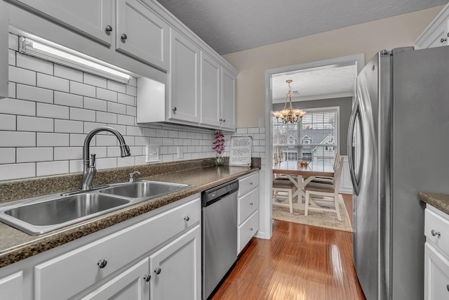 kitchen featuring dark countertops, dark wood-type flooring, appliances with stainless steel finishes, and a sink