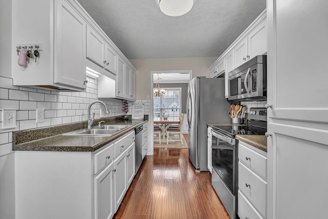 kitchen featuring white cabinets, appliances with stainless steel finishes, dark wood-type flooring, and a sink