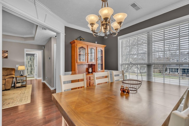 dining area featuring dark wood finished floors, visible vents, and ornamental molding