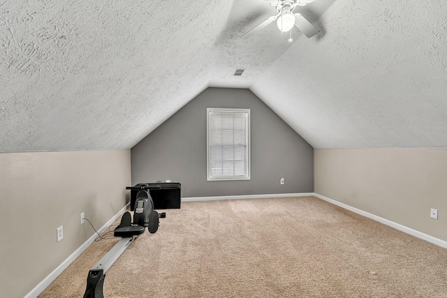 exercise area featuring lofted ceiling, carpet, visible vents, and baseboards