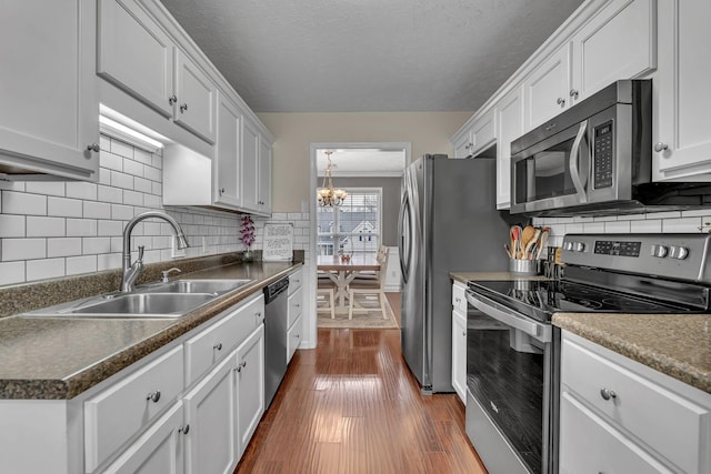 kitchen featuring dark wood-style flooring, appliances with stainless steel finishes, white cabinetry, and a sink