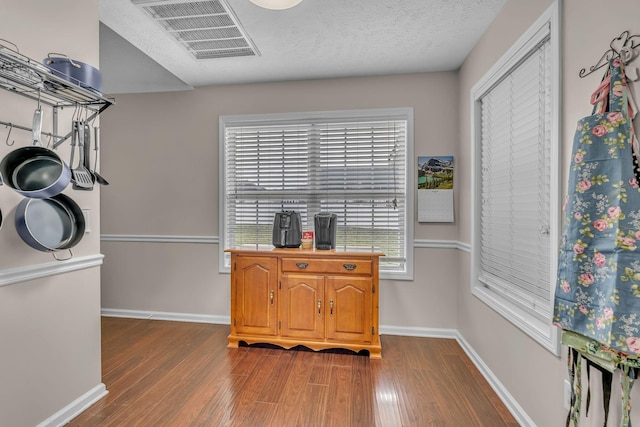 interior space with dark wood finished floors, visible vents, a textured ceiling, and baseboards