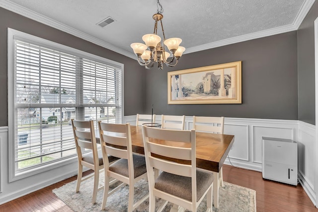 dining area featuring a notable chandelier, dark wood-type flooring, visible vents, and ornamental molding