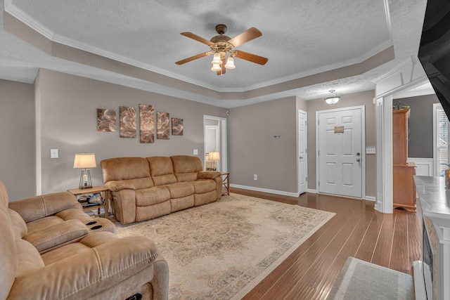 living room featuring a textured ceiling, dark wood-type flooring, ceiling fan, and ornamental molding