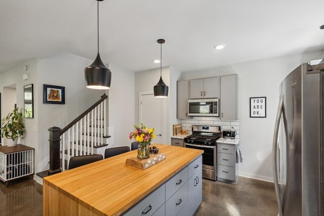 kitchen featuring butcher block countertops, backsplash, appliances with stainless steel finishes, and gray cabinetry