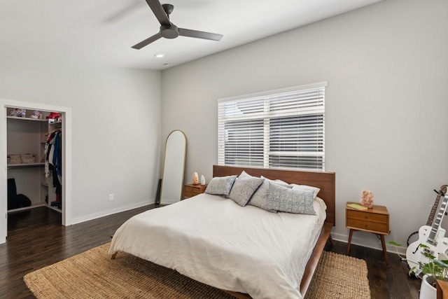 bedroom with a walk in closet, baseboards, and wood finished floors