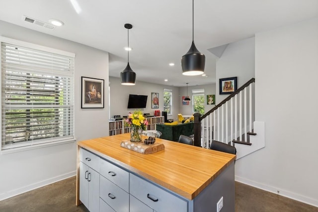 kitchen featuring visible vents, a kitchen island, finished concrete flooring, butcher block counters, and baseboards