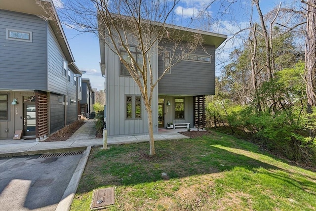 view of front facade with board and batten siding, a front yard, and a patio