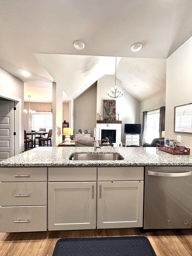 kitchen featuring a sink, an inviting chandelier, open floor plan, and stainless steel dishwasher