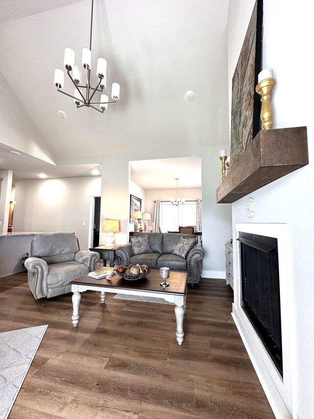 living room with baseboards, a chandelier, a fireplace, wood finished floors, and high vaulted ceiling