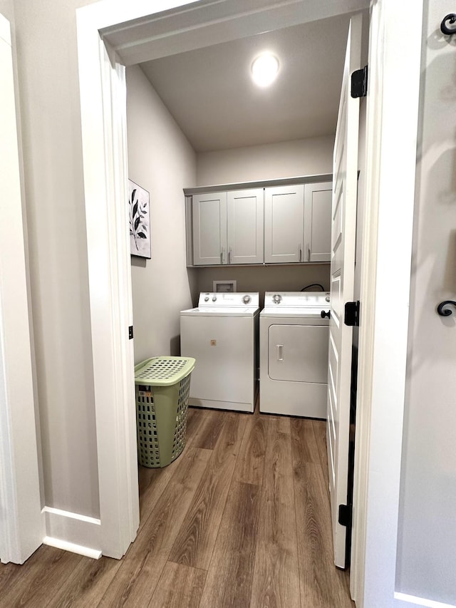 washroom featuring cabinet space, wood finished floors, and separate washer and dryer