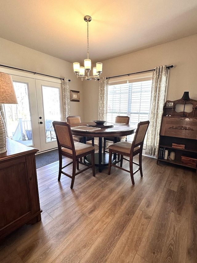 dining area featuring french doors, plenty of natural light, a notable chandelier, and wood finished floors