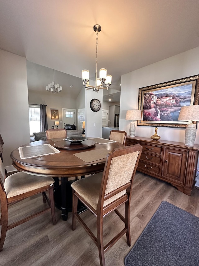 dining area featuring lofted ceiling, an inviting chandelier, and wood finished floors