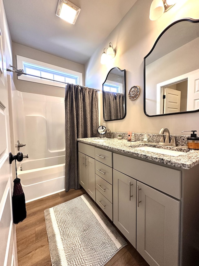 full bathroom featuring double vanity, wood finished floors, shower / bath combo, and a sink