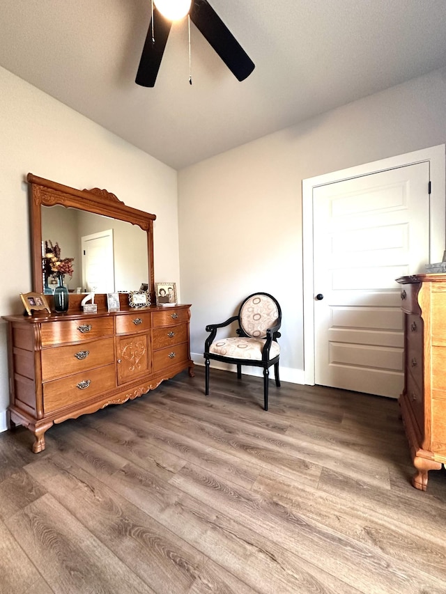 living area with ceiling fan, baseboards, and dark wood-style floors