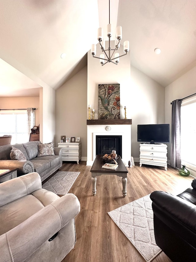 living room with plenty of natural light, an inviting chandelier, wood finished floors, and a fireplace