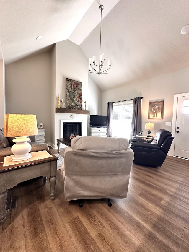 living area featuring wood finished floors, a notable chandelier, a fireplace with raised hearth, and vaulted ceiling