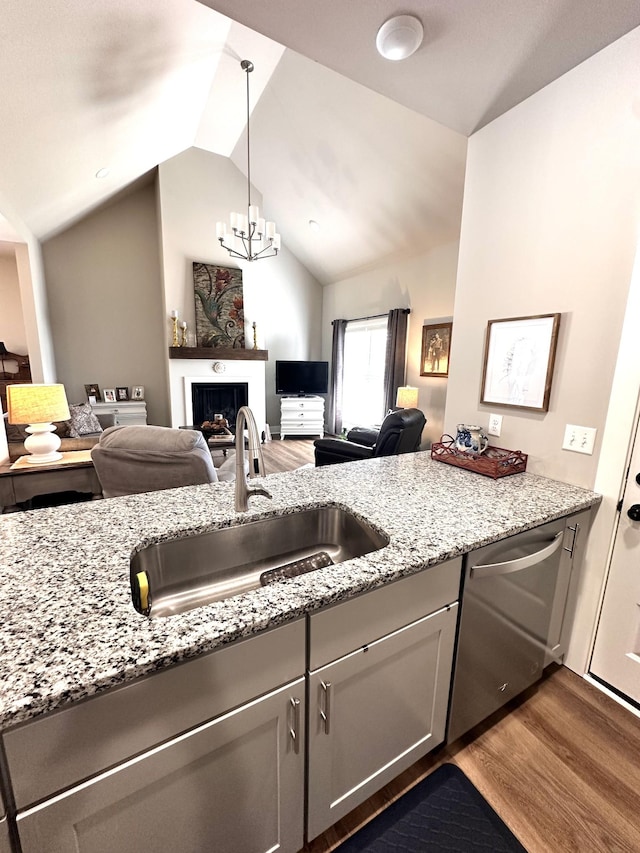 kitchen featuring stainless steel dishwasher, a fireplace, open floor plan, and a sink