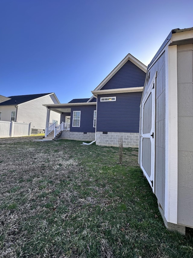 exterior space featuring an outdoor structure, a storage unit, a yard, and crawl space