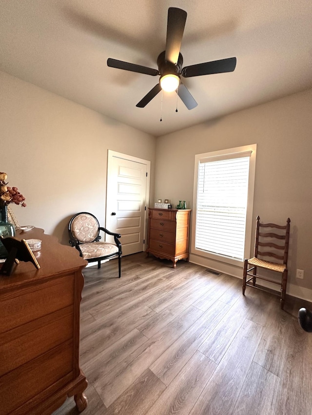 sitting room with a ceiling fan and light wood finished floors