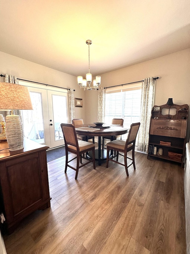 dining space with a chandelier, plenty of natural light, french doors, and wood finished floors