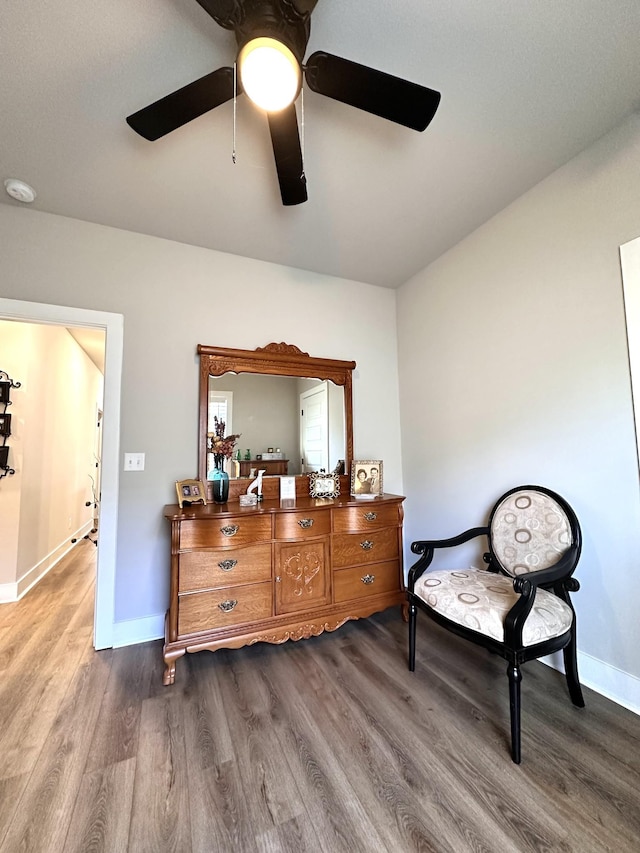 living area featuring dark wood-type flooring, baseboards, and ceiling fan