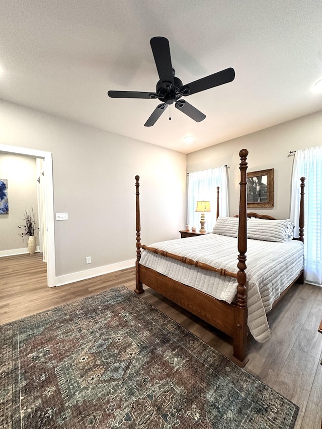 bedroom featuring baseboards, wood finished floors, and a ceiling fan