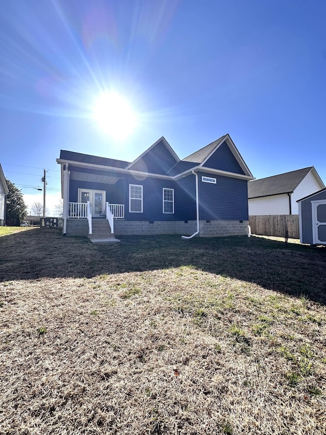 rear view of house with a yard, an outbuilding, a storage shed, and fence