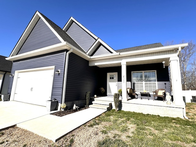 view of front of home with a porch, an attached garage, concrete driveway, and roof with shingles