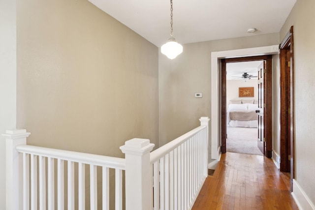 hallway featuring baseboards, an upstairs landing, and wood-type flooring