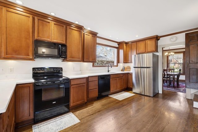 kitchen with a sink, brown cabinets, black appliances, and dark wood-style floors