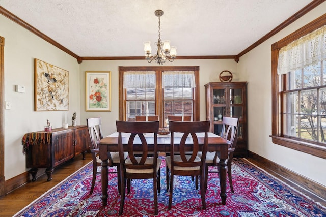 dining room featuring a textured ceiling, an inviting chandelier, wood finished floors, and crown molding