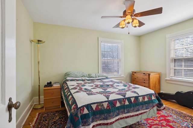 bedroom with multiple windows, baseboards, and wood finished floors