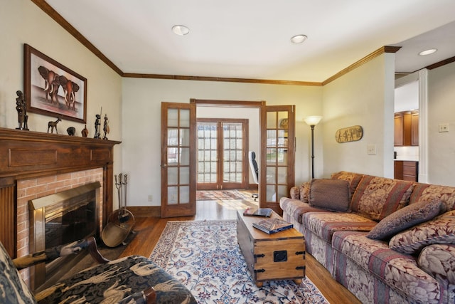 living room with wood finished floors, a brick fireplace, french doors, and ornamental molding