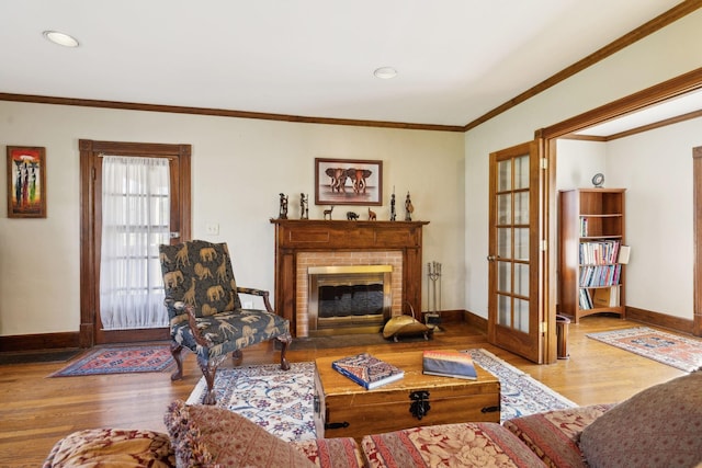 living room featuring ornamental molding, a brick fireplace, baseboards, and wood finished floors