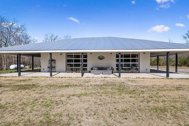 rear view of house featuring outdoor lounge area, a patio, and metal roof