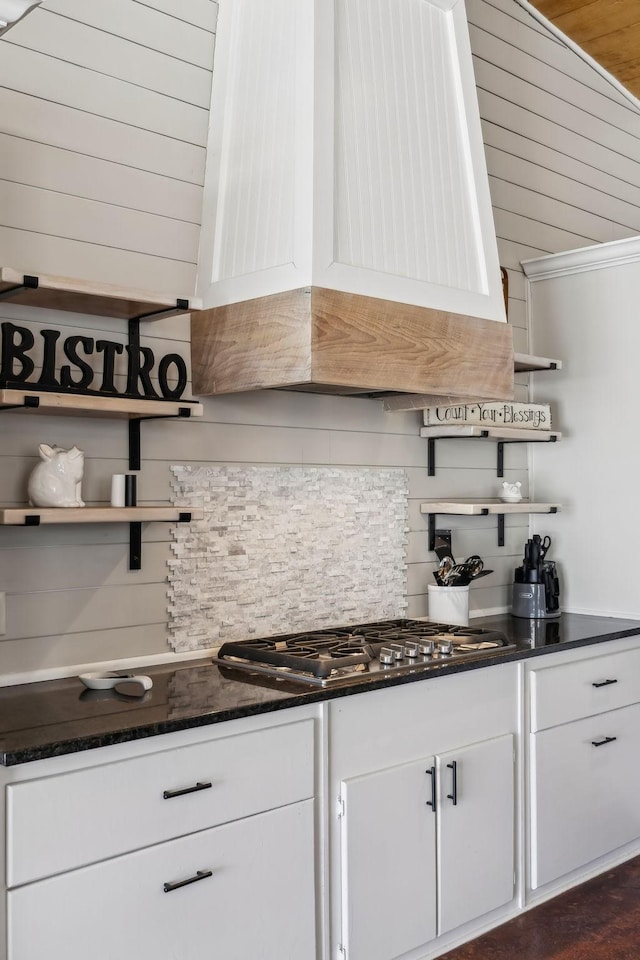 kitchen with stainless steel gas cooktop, dark stone counters, custom exhaust hood, white cabinetry, and open shelves