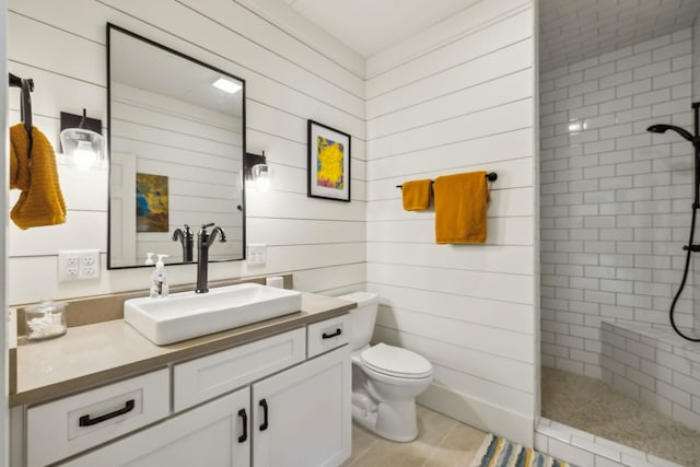 full bath featuring vanity, toilet, wood walls, and tiled shower