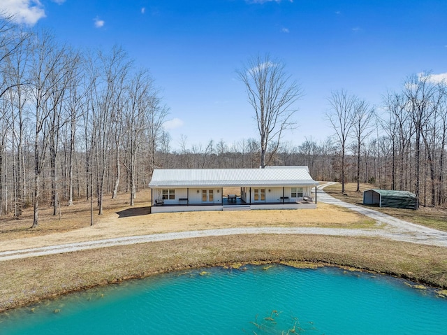 back of property with a lawn, covered porch, and metal roof