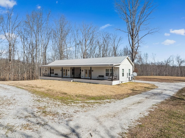 view of front of property with a porch, metal roof, and dirt driveway