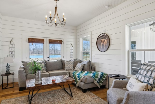 living room with a notable chandelier, french doors, and wood finished floors