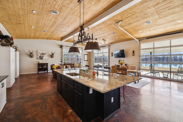 kitchen with a sink, concrete flooring, dark cabinets, and wood ceiling