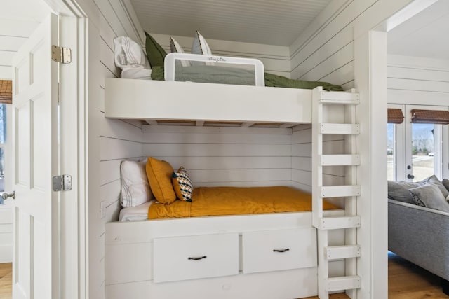 bedroom with access to outside, wood finished floors, and wood walls