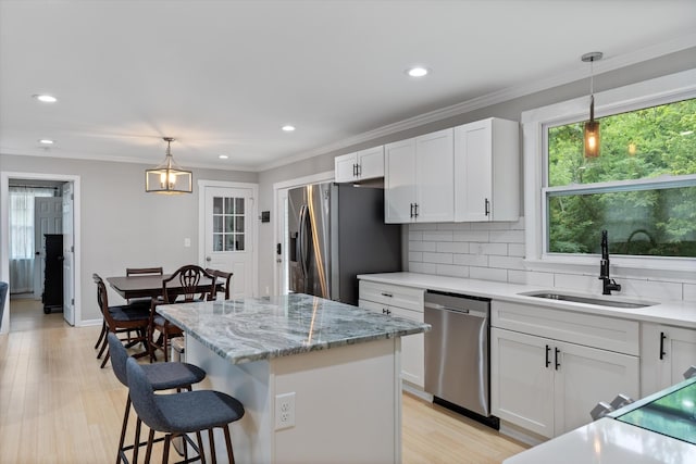 kitchen featuring a sink, backsplash, stainless steel appliances, a breakfast bar area, and white cabinets