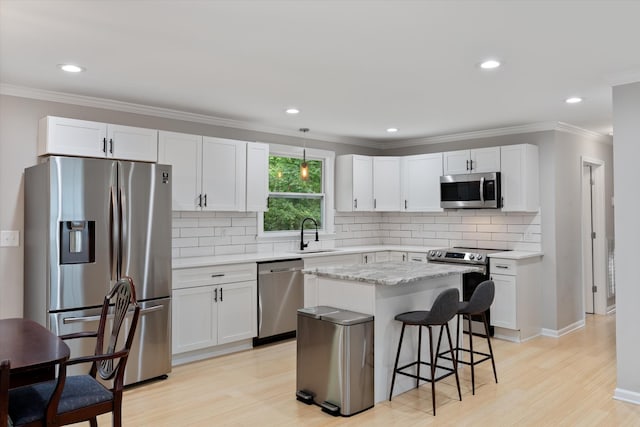 kitchen featuring crown molding, a breakfast bar, light wood-type flooring, stainless steel appliances, and a sink