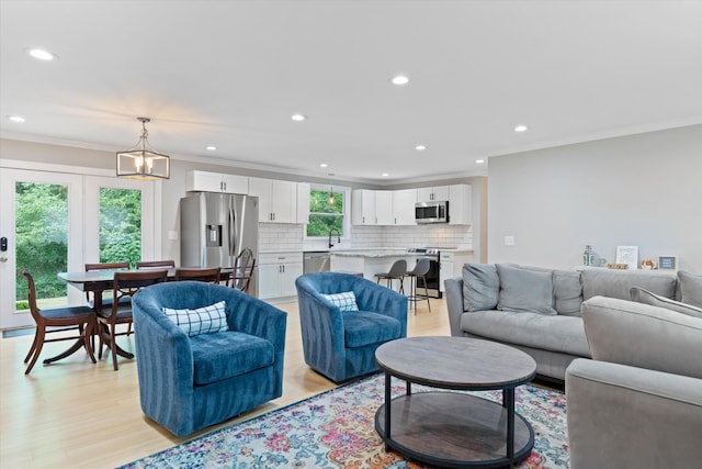 living area with recessed lighting, light wood-type flooring, and ornamental molding